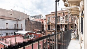 A balcony with a view of a cityscape, featuring buildings with balconies and a red-tiled roof. - GuestHost - Cozy 70 sqm apartment, perfect for two people, located on the third floor of a period building in good condition with a lift (NOT suitable for disabled people). The property is located along via Etnea, the main shopping street in Catania, and (Catania)