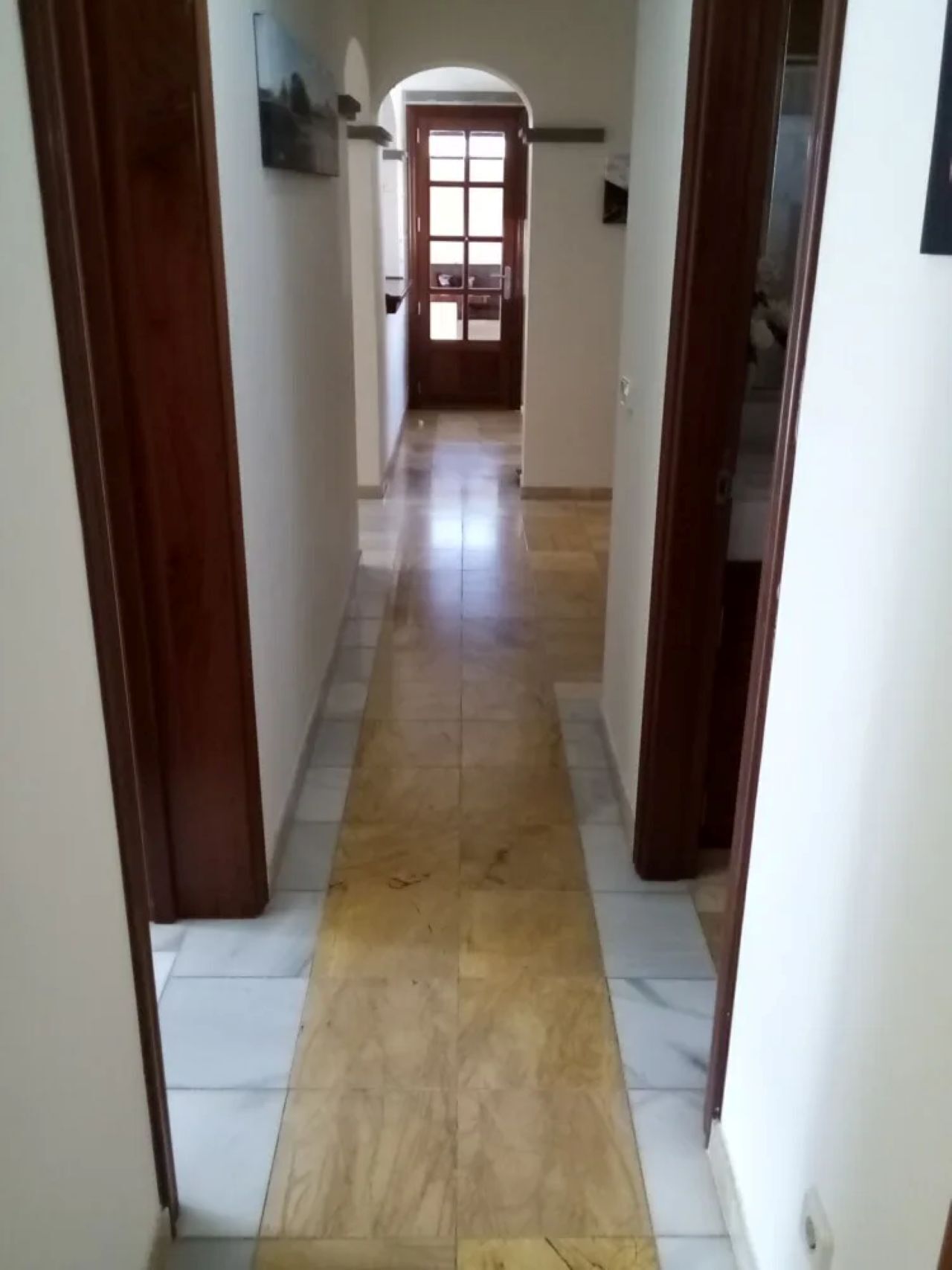 A hallway with a tiled floor and wooden doors.
