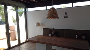 Et værelse med en træbænk, en hængende vævet lampe og en gulvlampe.