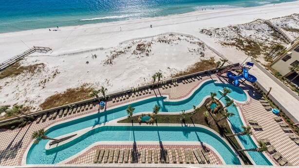 Vue aérienne d’un complexe hôtelier doté d’une piscine, d’une plage et donnant sur l’océan.
