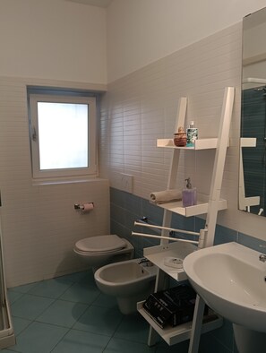 Ein Badezimmer mit Toilette, Bidet, Waschbecken und Fenster.