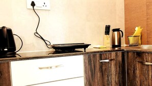 Una cocina con una encimera, cafetera, hervidor y tostadora. Hay un enchufe en la pared.
