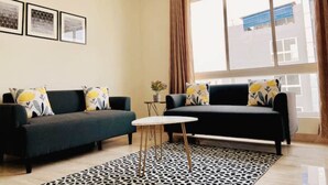 Una sala de estar moderna con dos sofás oscuros, una mesita redonda y un tapete estampado.