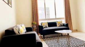 Una sala de estar con un sofá, una mesita redonda y una alfombra estampada.