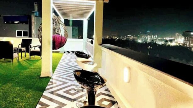 Un balcón con piso estampado, una silla y un sillón colgante.
