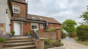 A traditional brick house with a white door, a small front garden, and a paved driveway leading to a wooden gate. - Lime Kiln Farm, Malton, North York Moors (Malton)