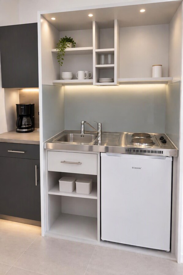 A compact kitchen with a built-in stove, two sinks, and storage cabinets.