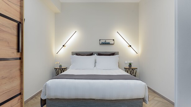 Un dormitorio moderno con una cama grande, dos mesitas de noche y un letrero en la pared.