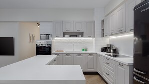 Una cocina moderna con armarios blancos, una isla central y un refrigerador negro.