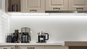 Una cocina con armarios blancos, una cafetera y un hervidor sobre la encimera.
