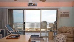 Ein Wohnzimmer mit einer Couch, einem Sessel, einem Couchtisch und einem Balkon mit Meerblick.