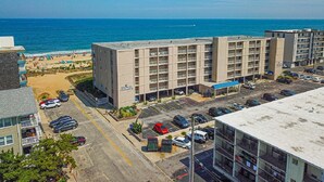Ein mehrstöckiges Hotel mit Parkplatz vor der Tür, in Strandnähe gelegen.