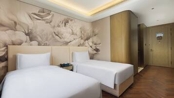 A hotel room with two beds, a wooden wardrobe, and a floral mural on the wall.