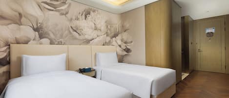 A hotel room with two beds, a wooden wardrobe, and a floral mural on the wall.