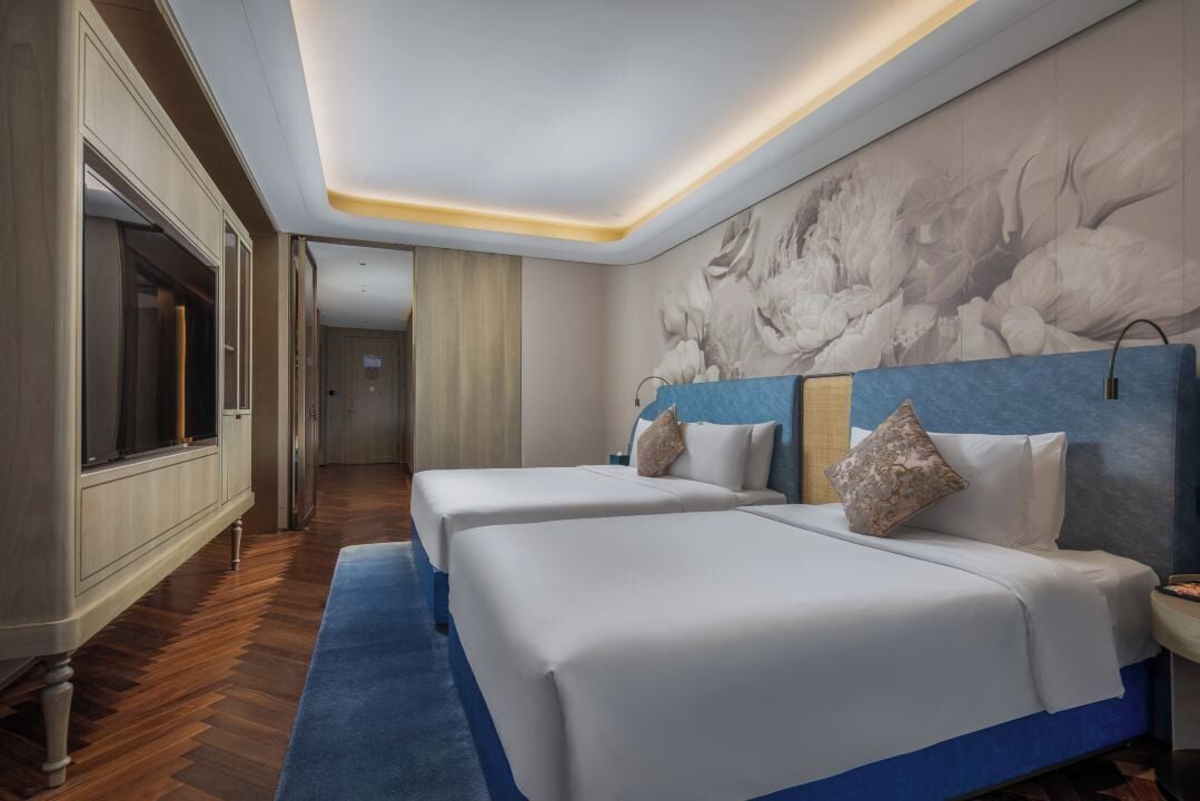 Habitación de hotel con dos camas, un mural grande en la pared y suelo de madera.