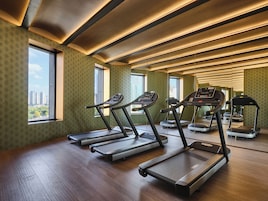 A gym with treadmills, exercise bikes, and a mirrored wall.