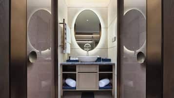 Un bagno moderno con un lavandino centrale, uno specchio grande e due portasciugamani.