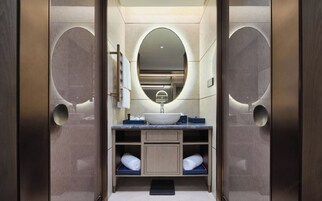 Un bagno moderno con un lavandino centrale, uno specchio grande e due portasciugamani.
