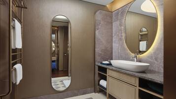 Un baño moderno con un espejo grande, un lavabo blanco y un perchero para toallas.