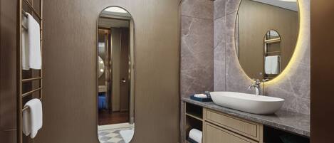 A modern bathroom with a large mirror, a white sink, and a towel rack.