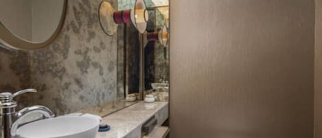 Une salle de bain moderne avec un grand lavabo en marbre, des toilettes et un miroir agrémenté d’éléments décoratifs.