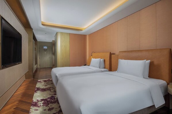 Una habitación de hotel con dos camas, un televisor y un pasillo que da a otras habitaciones.