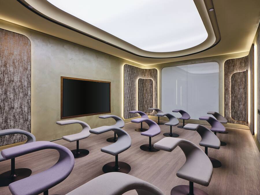 A modern room with curved seating, a large flat-screen TV, and a large window.