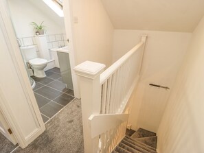 A staircase leading to a bathroom with a toilet, sink, and potted plant. - Stable Cottage (Matlock)