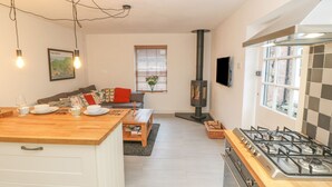 Eine moderne Küche mit einer zentralen Kochinsel, einem Einbauherd und einem Essbereich mit Sofa und Tisch.