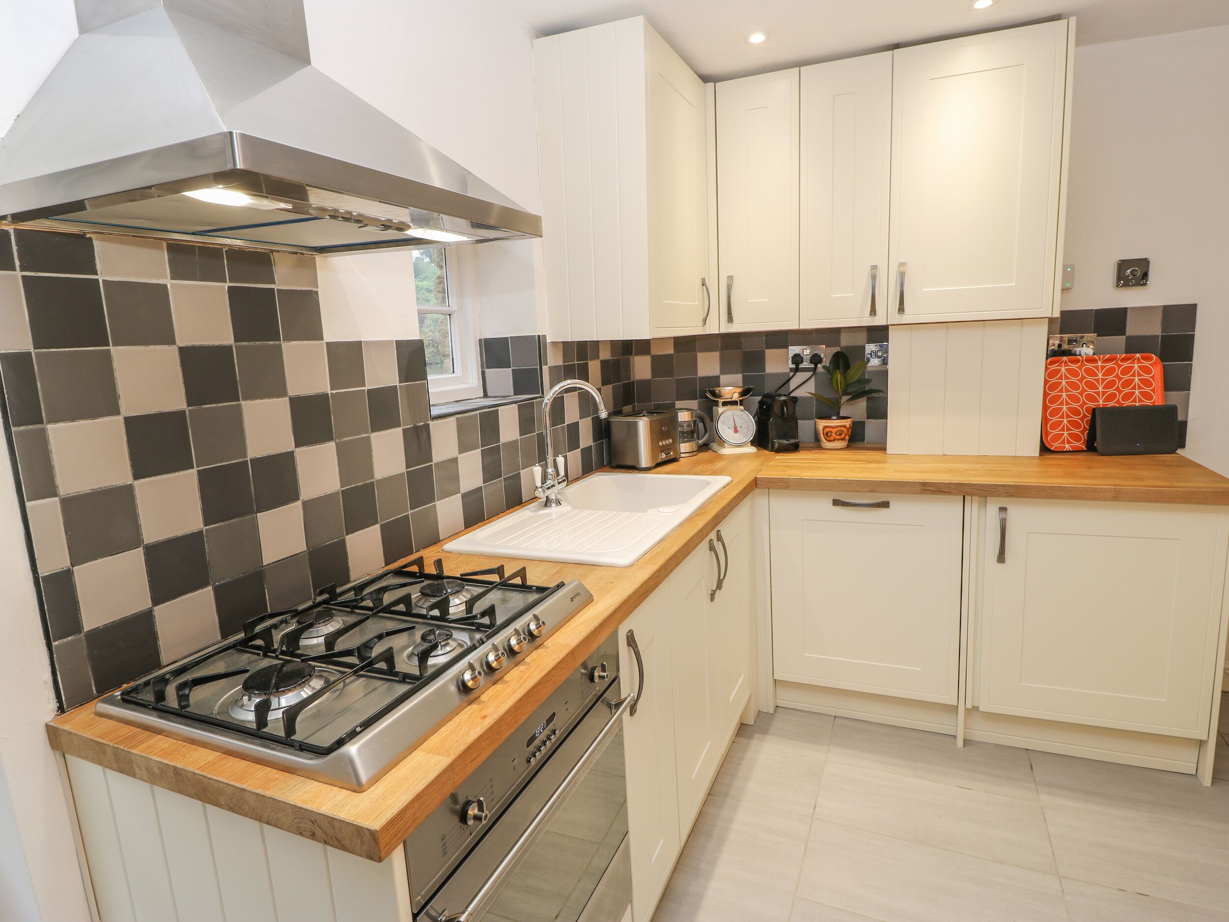 A kitchen with a gas stove, sink, and white cabinets.