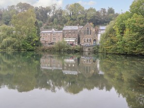 A calm river reflecting buildings, including a bookstore named 'Scarthin Books'. - Stable Cottage (Matlock)
