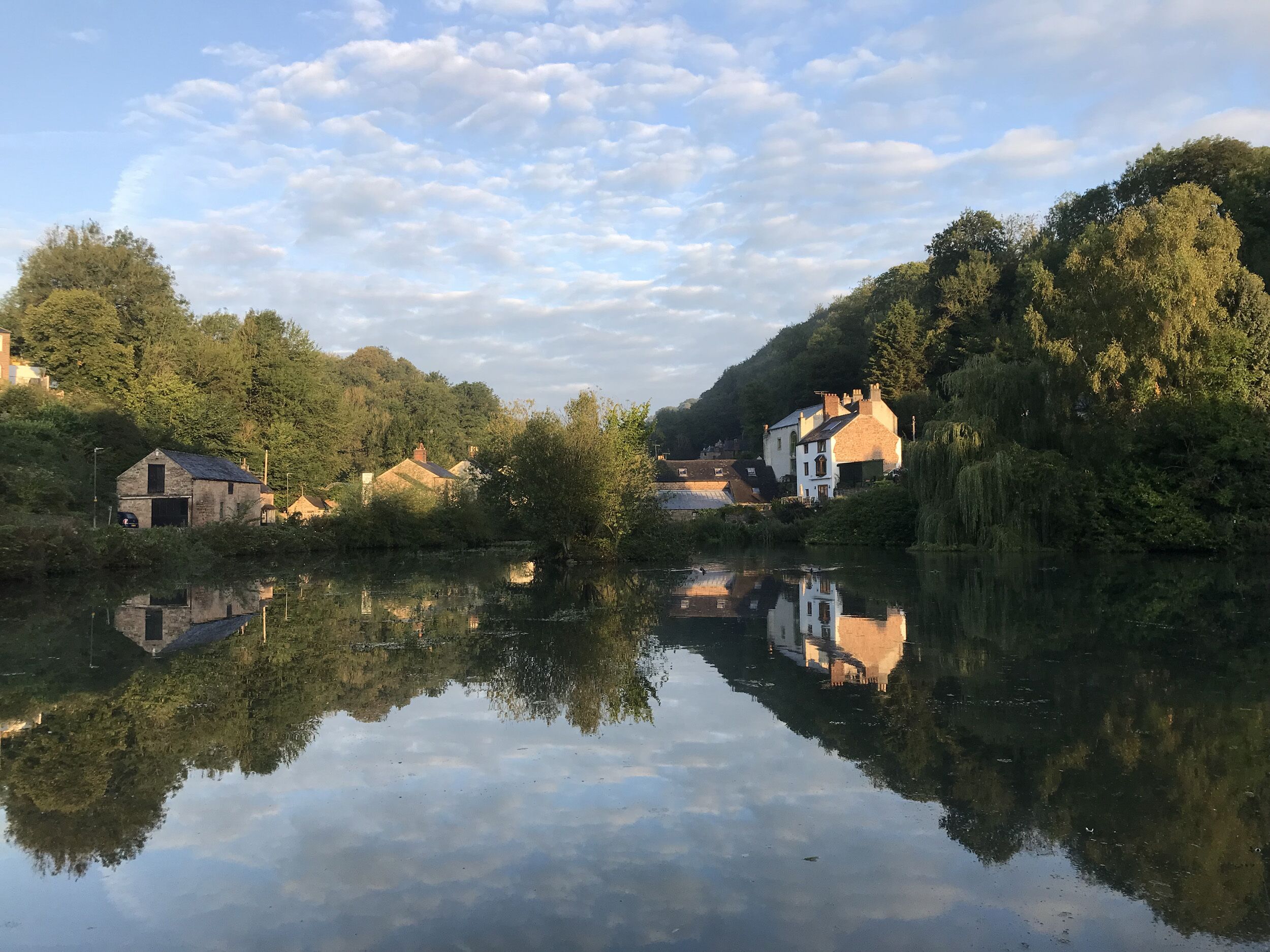 A calm river with reflections of buildings and trees.