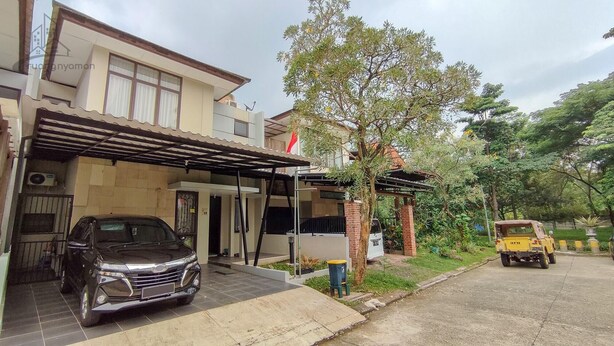 A two-story house with a covered driveway, a parked car, and a small yellow vehicle on the street. - Atmosfer Guest House Sentul by Ruang Nyaman (Sentul City)