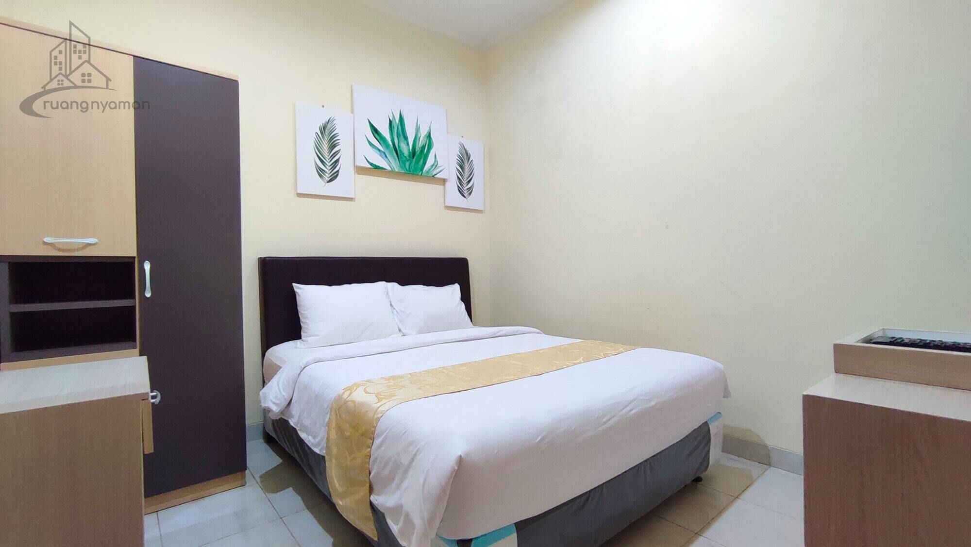 Un dormitorio con cama, armario e ilustraciones de plantas en la pared.