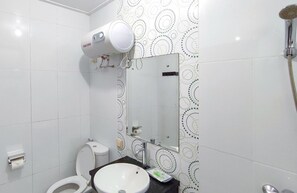 A bathroom with a toilet, sink, mirror, and a handheld showerhead. - Atmosfer Guest House Sentul by Ruang Nyaman (Sentul City)