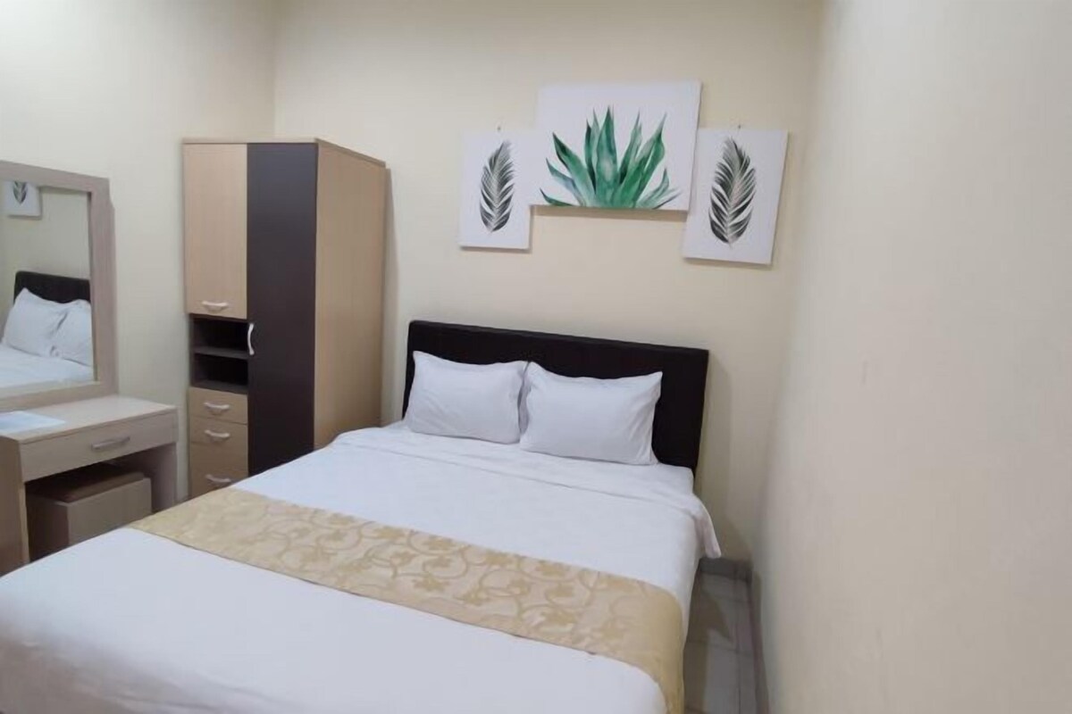 A hotel room with a bed, a wardrobe, a desk, and a mirror.