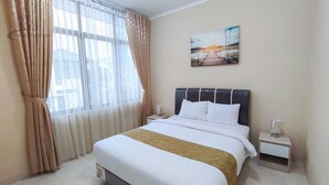 A hotel room with a bed, a nightstand, a lamp, and a painting on the wall. - Atmosfer Guest House Sentul by Ruang Nyaman (Sentul City)