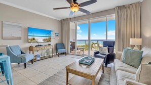 A spacious living room with a flat-screen TV, a ceiling fan, and a balcony with a view of the ocean. - Gulf 513-2 BED/2 BATH-sleeps 6-VIEWS OF POOL AND BEACH!  Updated (Fort Walton Beach)
