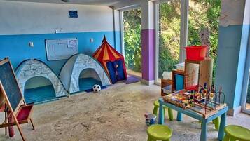 Um quarto com duas tendas, uma mesa com brinquedos e um quadro negro.