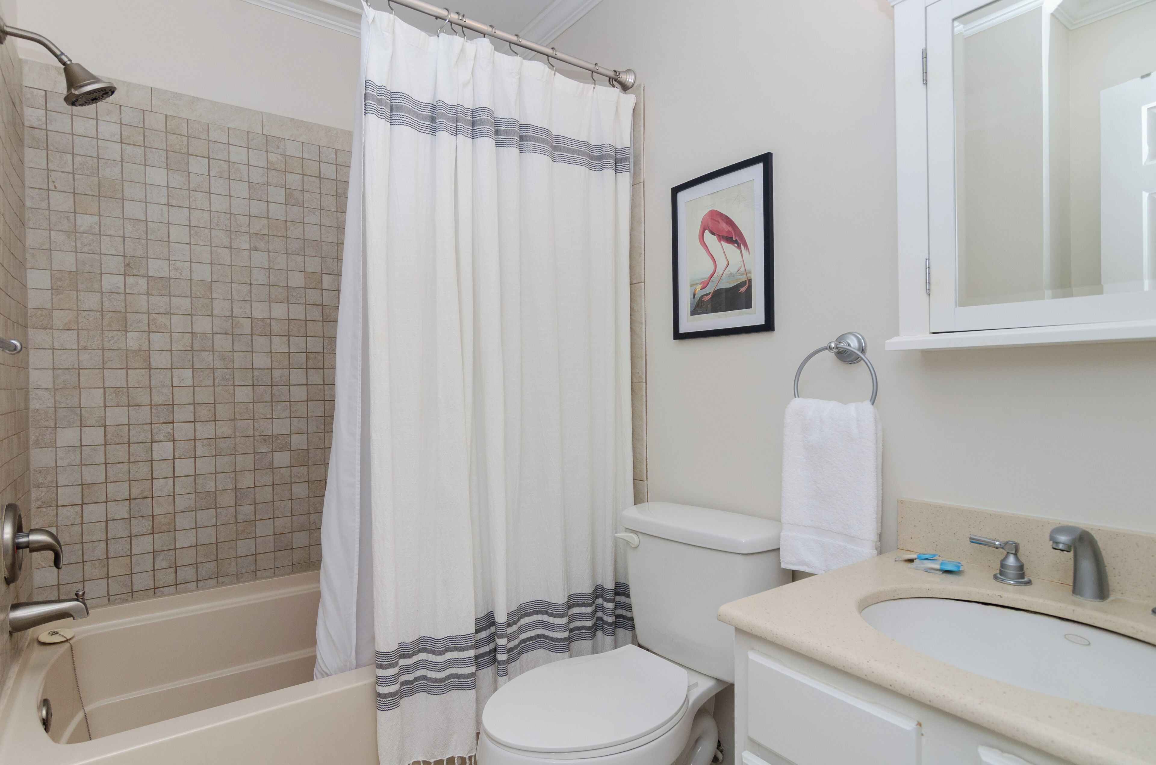 A bathroom with a bathtub, toilet, sink, and a framed picture on the wall.