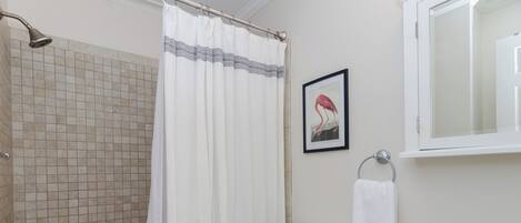 A bathroom with a bathtub, toilet, sink, and a framed picture on the wall.