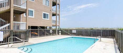 A rectangular swimming pool with a 3 FT depth marking, surrounded by a wooden deck and a metal fence.