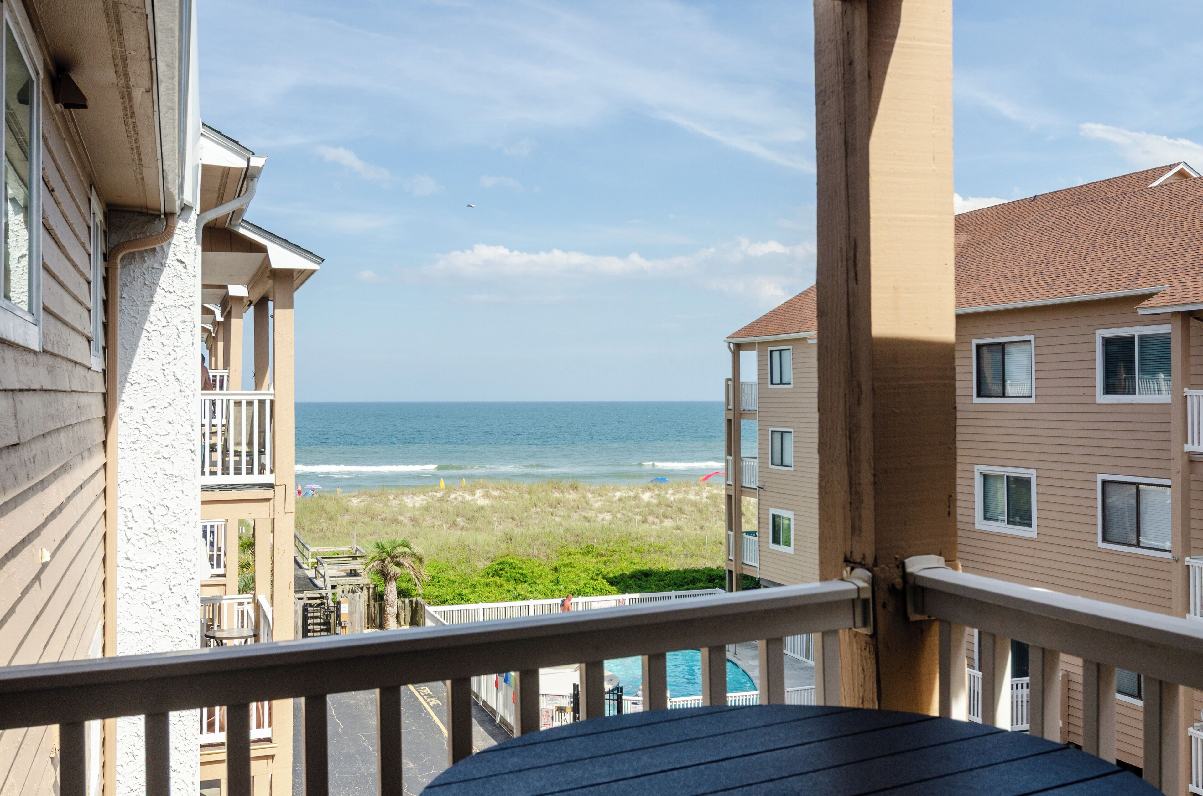 A balcony with a view of the beach and ocean.