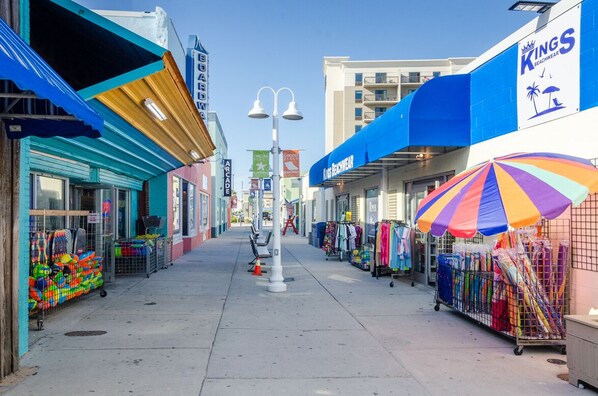 A boardwalk with shops, including a beachwear store and a colorful umbrella.