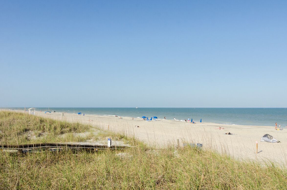Ein Strand mit einer Holzpromenade, Strandstühlen und Zelten.