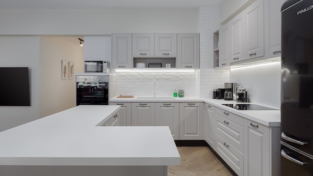 Une cuisine moderne avec des meubles blancs, un îlot central et des appareils électroménagers intégrés.