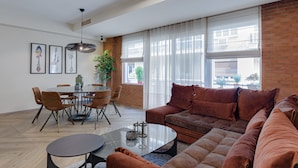 Un salon moderne avec un canapé marron, une table basse en verre et un coin repas comprenant des chaises et une table.