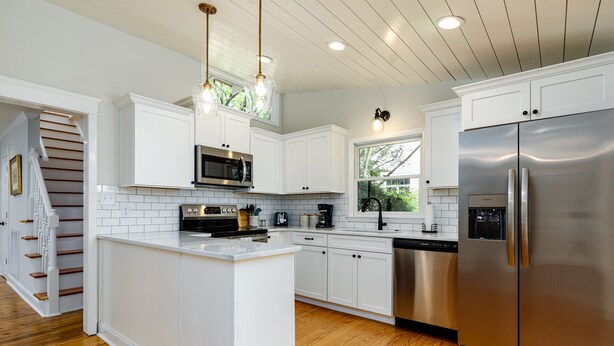 A modern kitchen with white cabinetry, a stainless steel refrigerator, and a wooden island. - Historic Cottage in the heart of Pinehurst Village (Pinehurst)
