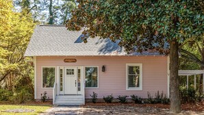 A pink house named "The Pink Cottage" with a white door, two windows, and a small porch. - Historic Cottage in the heart of Pinehurst Village (Pinehurst)
