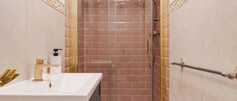 Un baño con ducha, lavamanos y espejo.